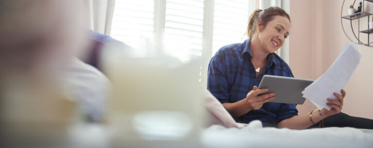 Young woman sat on her bed reading through paperwork