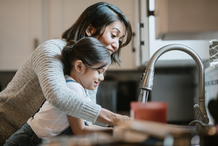 A mom teaches her little girl how to properly wash her hands