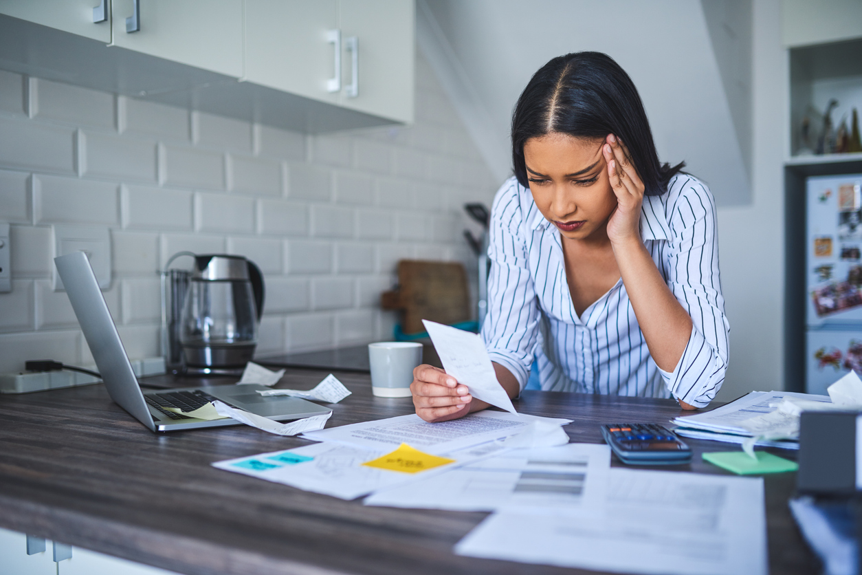 woman standing alone and feeling stressed while going through her finances in her home