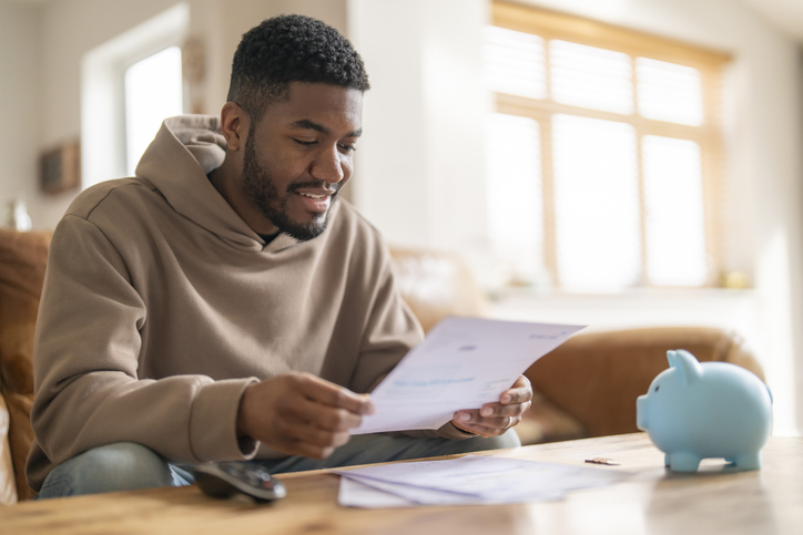 smiling man reading letter when managing finances